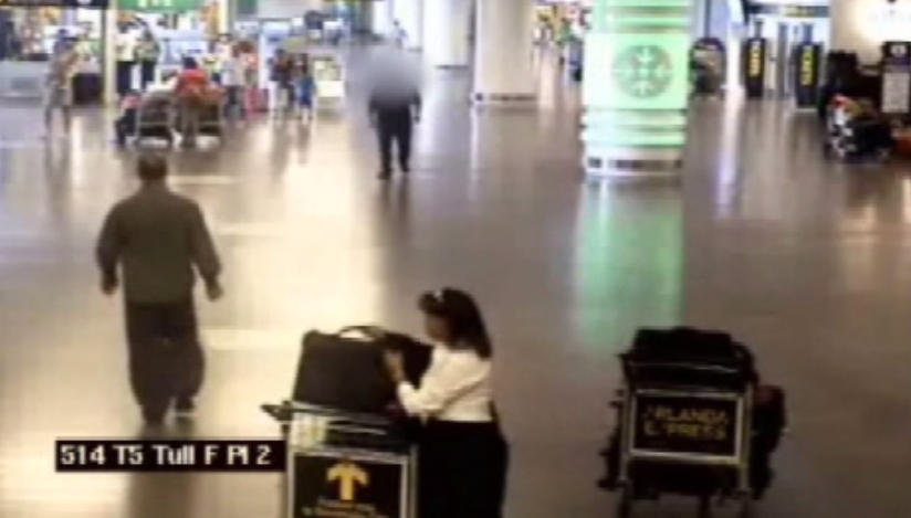 Här syns en kvinna stjäla en annan väska från en vagn.