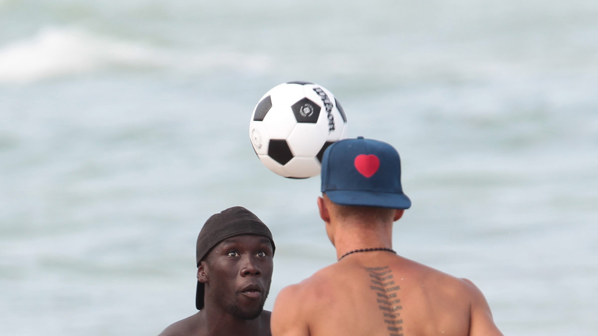 De lirar lite fotboll på stranden. 