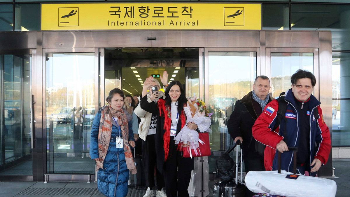 Glada ryska turister kommer ut i solen på Pyongyangs internationella flygplats.