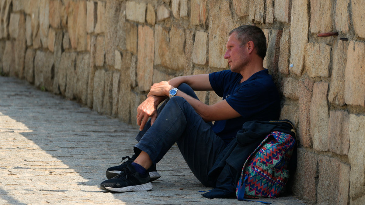 En man vilar i skuggan vid en stenmur i Madrid i juli. Arkivbild.