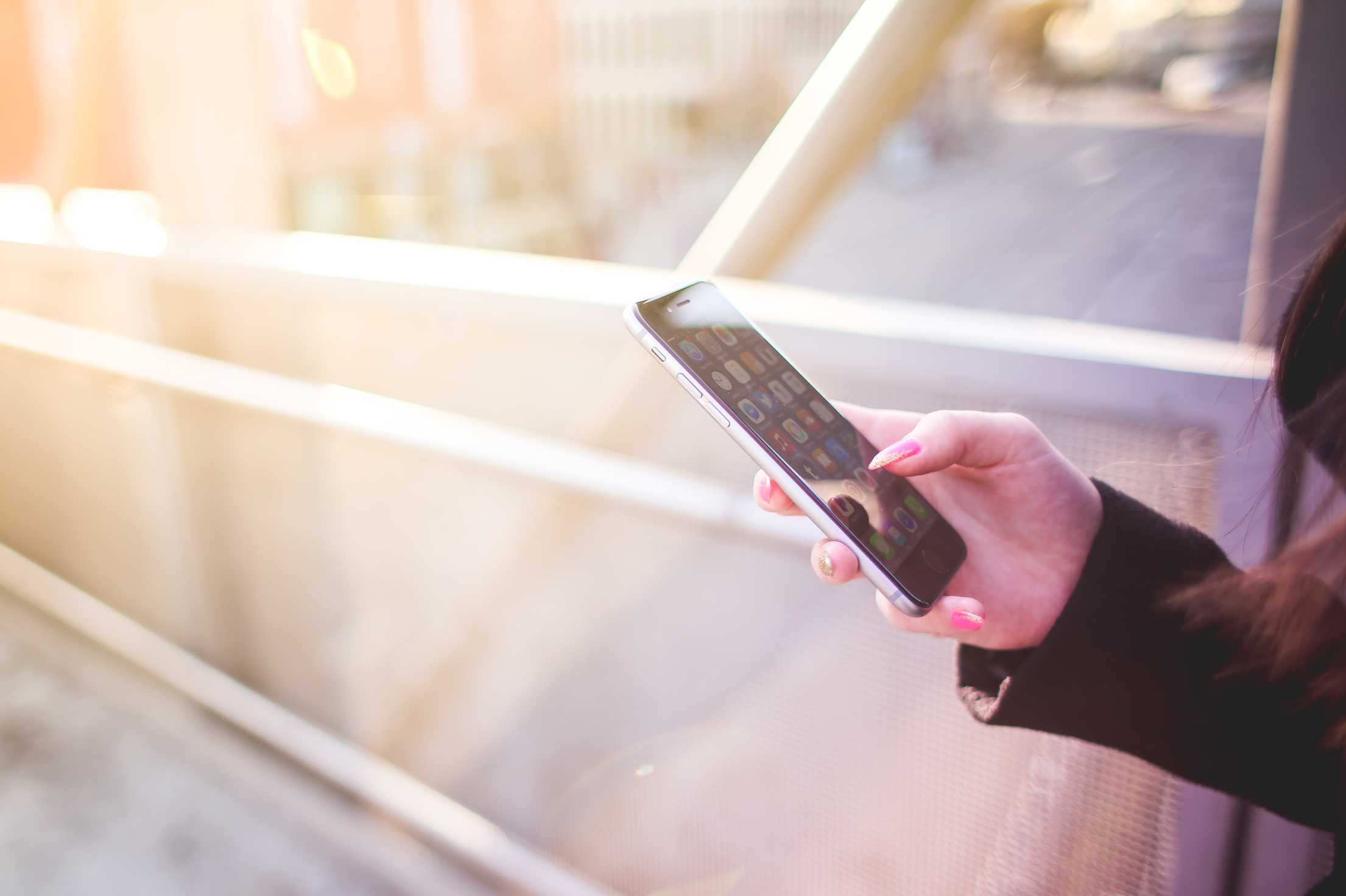 En kvinna som håller i sin iPhone En kvinna som håller i sin iPhone
