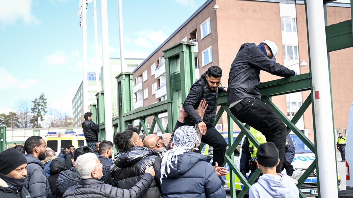 Människor i Rinkeby försökte lugna upprörda män och få dem att klättra ner från ett stängsel.