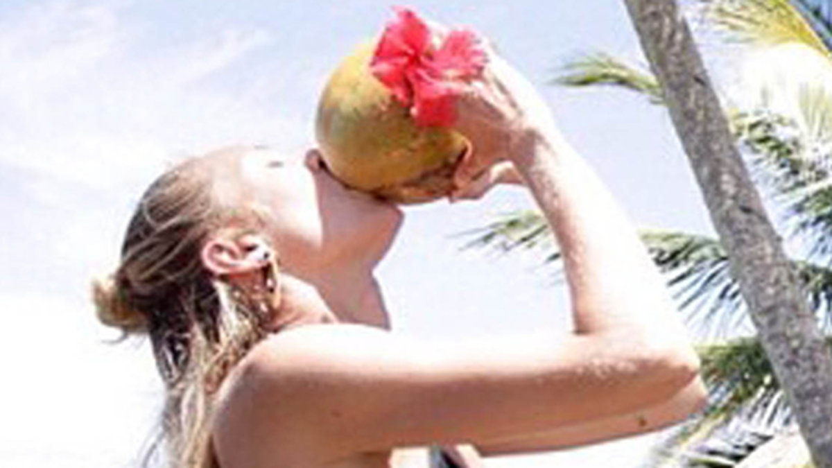 Candice Swanepoel dricker ur en kokosnöt. 