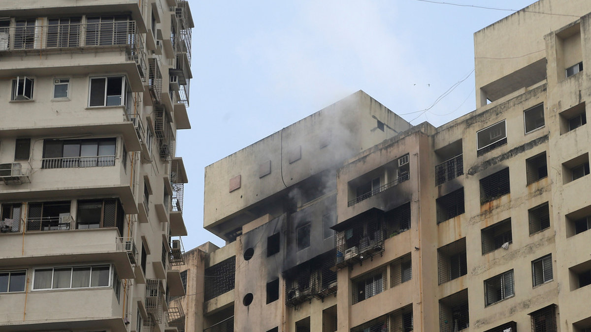 Rök stiger från en brandhärjad byggnad i Bombay. Branden tog minst sex människors liv.