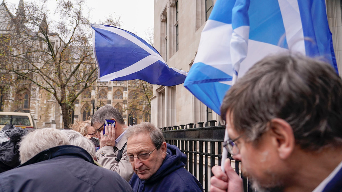 Demonstranter med skotska flaggor lyssnar på domslutet i sina telefoner utanför HD i London.