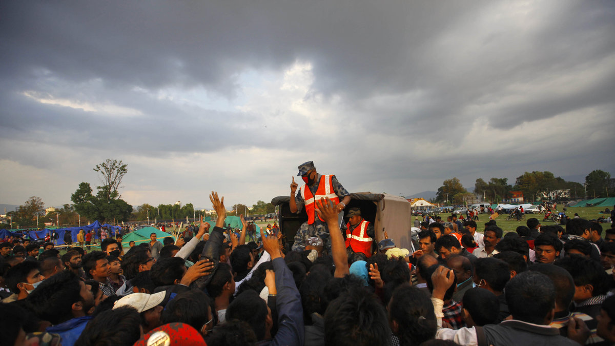 En nepalesisk polis ber offren från jordbävningen att ställa sig i kö för att få tält.