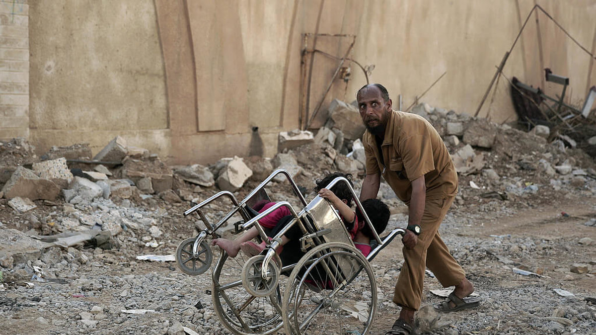 Här flyr en man med sina två små barn undan strider mellan IS och irakiska styrkor.