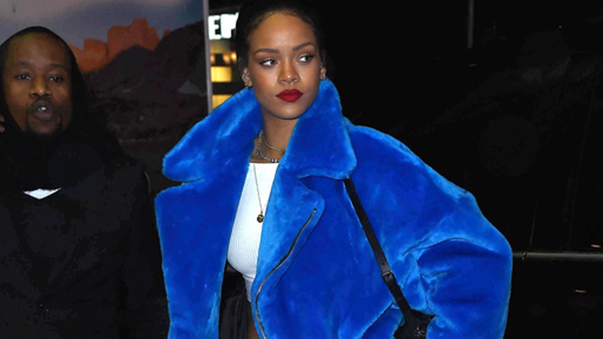 Rihanna värmer sig i en blå päls. 