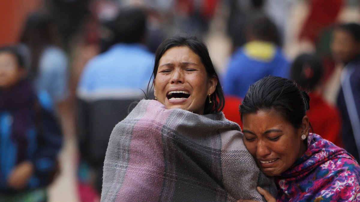 Överlevande familjemedlemmar bryter ihop under en kremering av ett av de tusentals offer som dött av jordbävningen.
