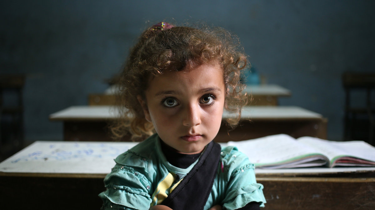 Flicka sitter i sin skolbänk i ett flyktingläger i Libanon, 2014. 