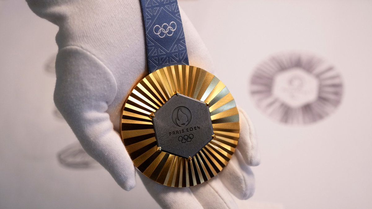 Så ser en guldmedalj i OS 2024 ut. Den sexkantiga mörka delen av medaljen består av järn från Eiffeltornet.