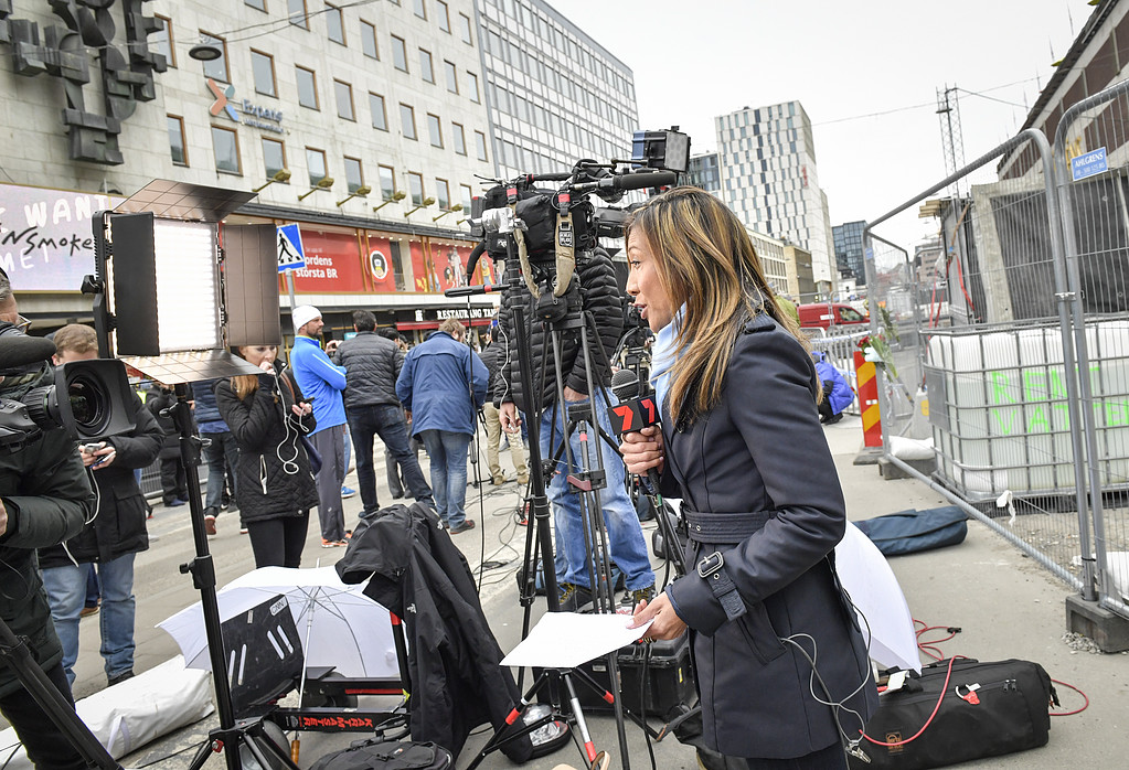 Journalist bevakar terrordådet Folksamling vid kamera