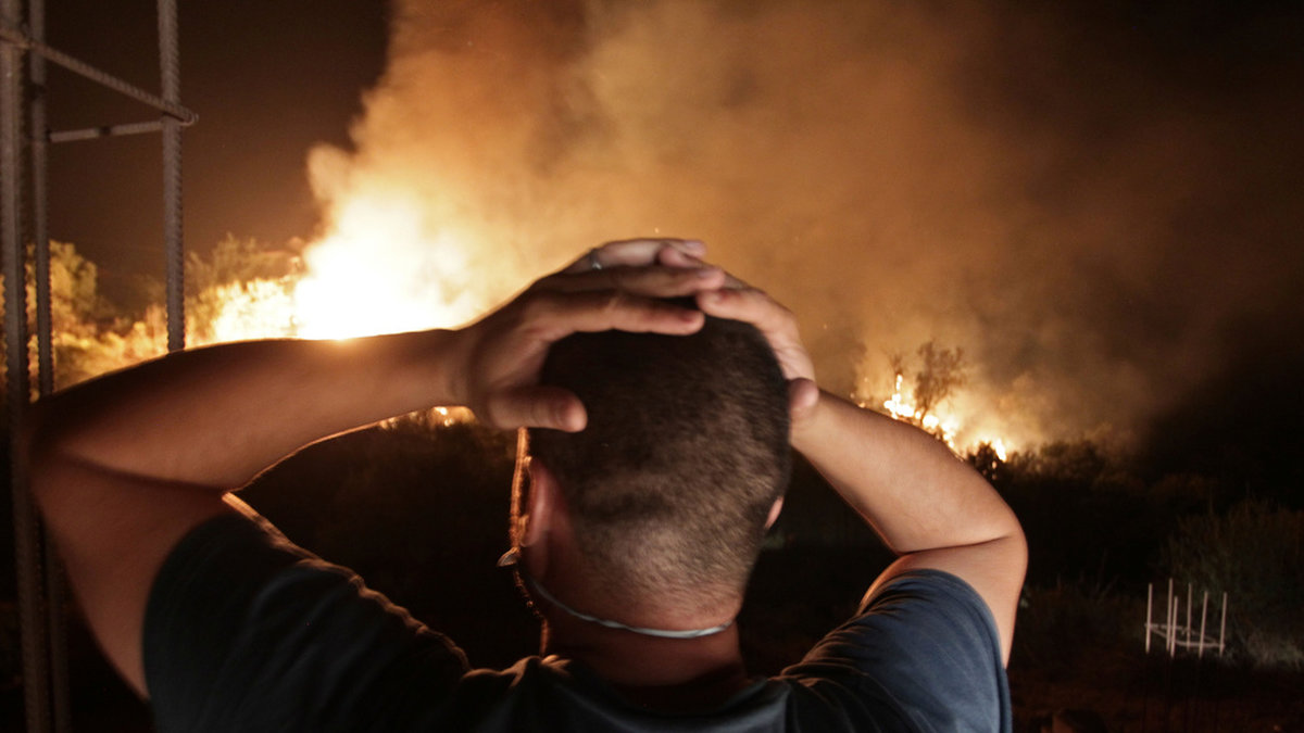 En algerisk man i den bergiga Kabyleregionen, öster om huvudstaden Alger, ser på en av de förödande skogsbränder som härjade i Algeriet i augusti förra året. Arkivbild.